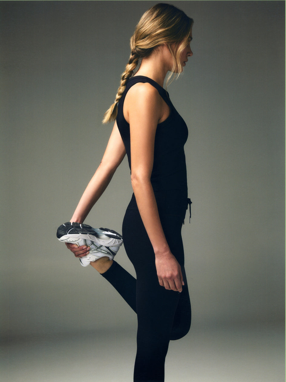 Black Women's Racerback Tank & Performance Leggings - Side Profile Stretch Pose | Greyson Clothiers