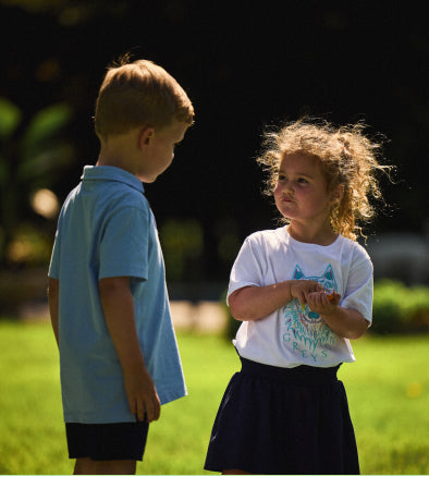 Two children standing on a grassy area with a blurred background