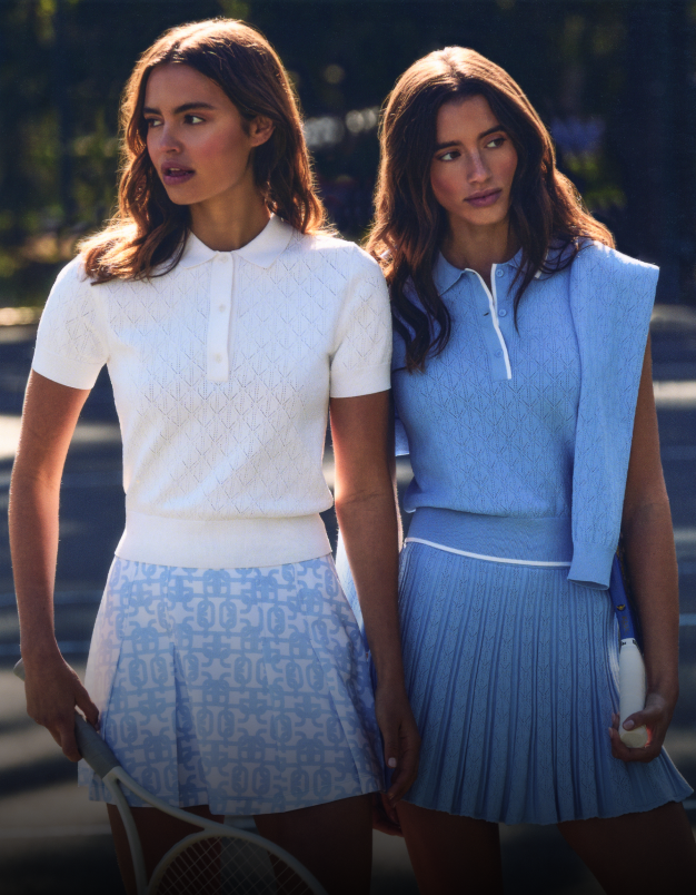 Two women in tennis attire standing on a court.